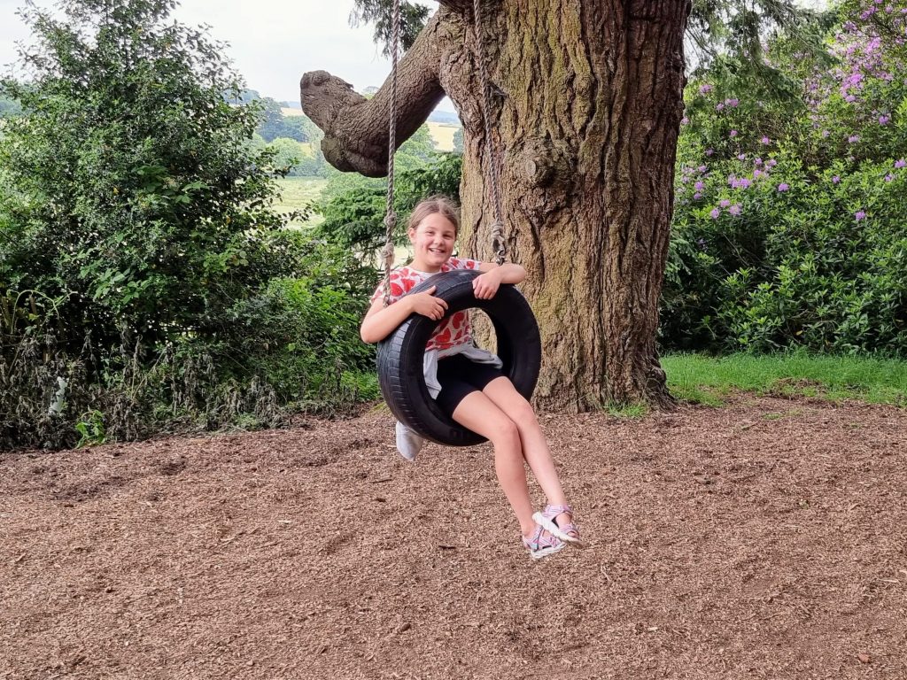 How to home educate on a budget, UK discounts, freebies & tips for travel, resources & days out guide, photo of frugal mum child on swing