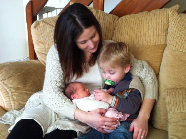 frugal mum with young children cuddling on sofa, two babies