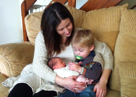 frugal mum with young children cuddling on sofa, two babies, how to claim child benefit online guide