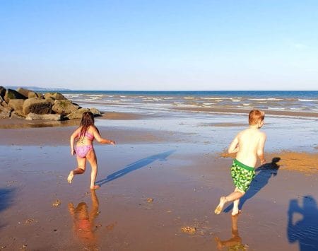 family saving challenges, frugal mum children running at beach