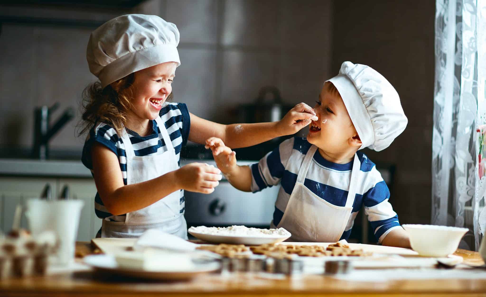 children cooking messing around in kitchen wearing chefs hats