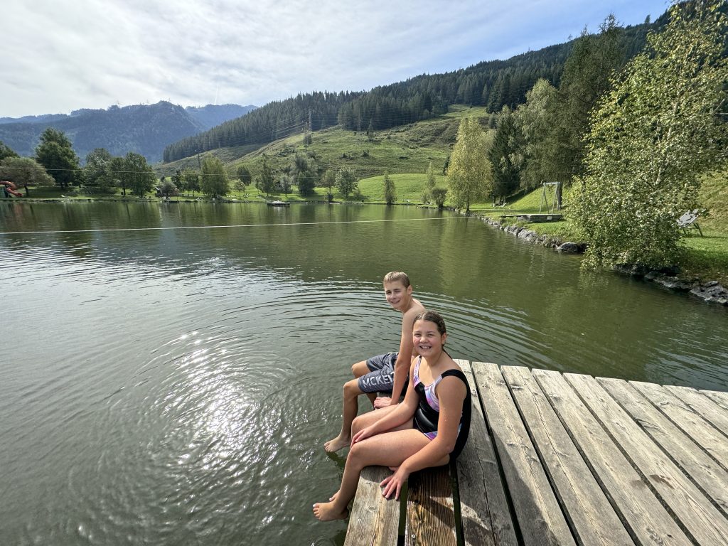 How to home educate on a budget, UK discounts, freebies & tips for travel, resources & days out guide, photo of frugal mum children by lake in Austria