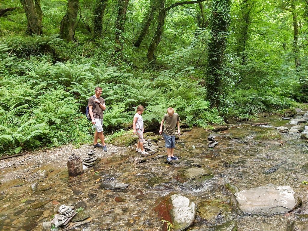 best things to do in Cornwall with kids, St Nectan's Glen, waterfall photo, frugal mum children and husband in stream